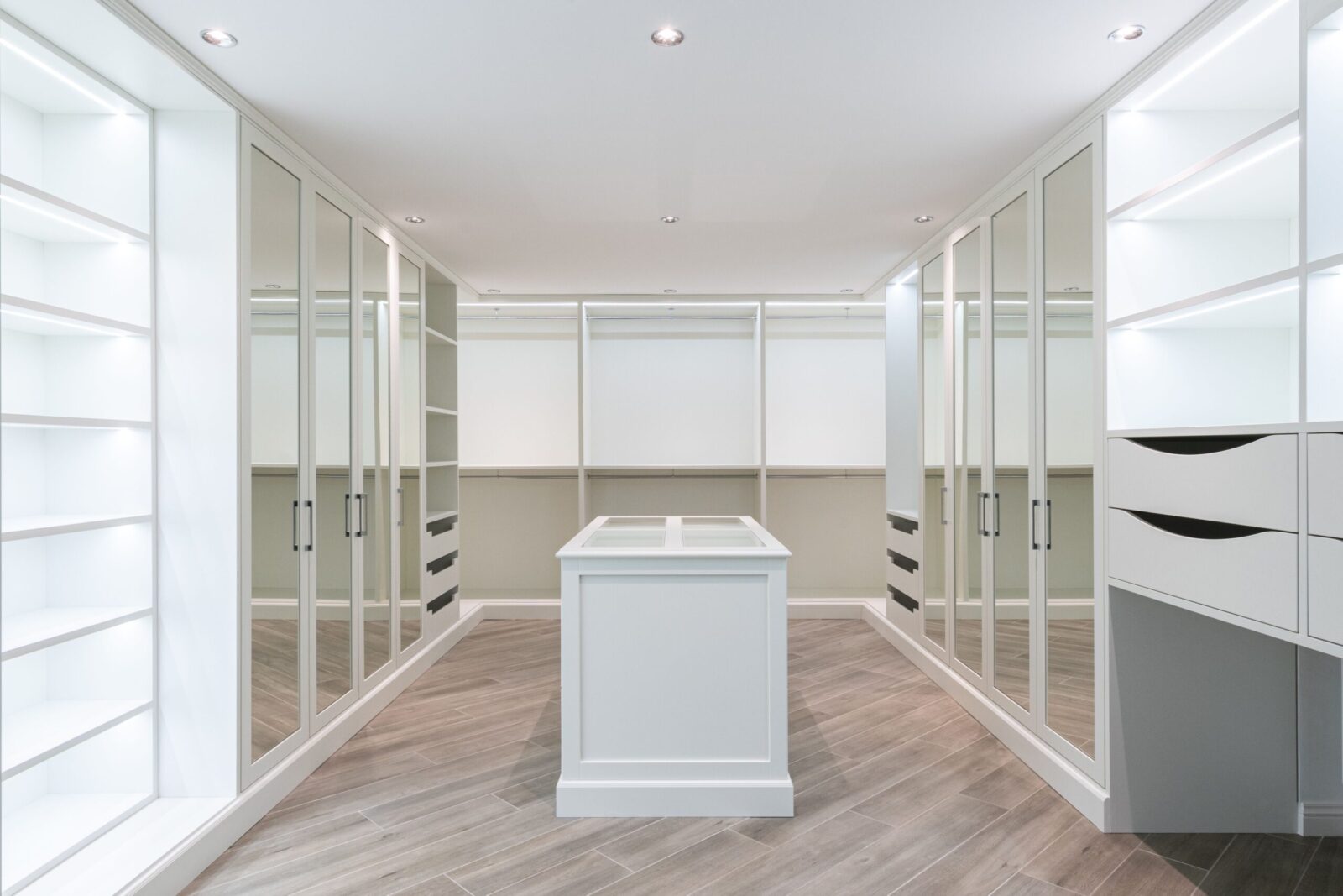 Interior of spacious minimalist walk in closet with empty shelves and mirrored doors in modern apartment